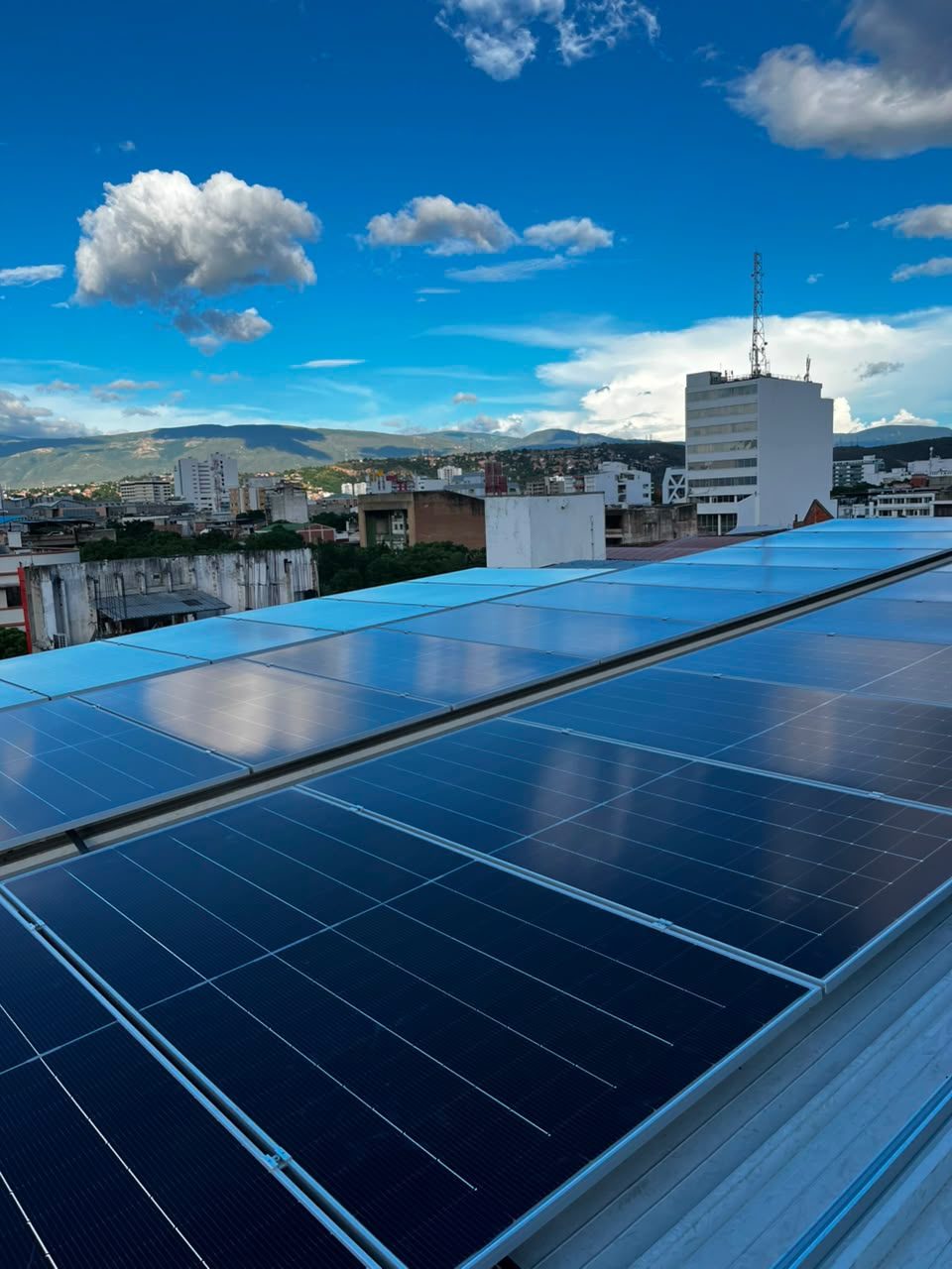 Paneles solares sobre una cubierta comercial con el cielo azul y las montañas de Cúcuta al fondo